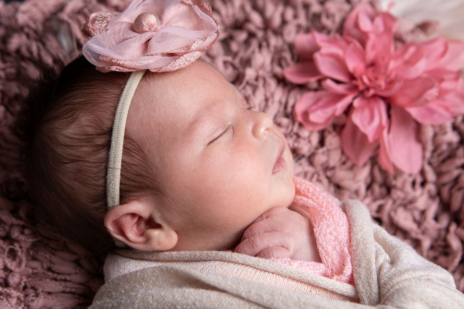 Sleeping newborn baby girl wearing a pink floral headband, photographer by Precious Keepsakes Photography in Boerne, Texas