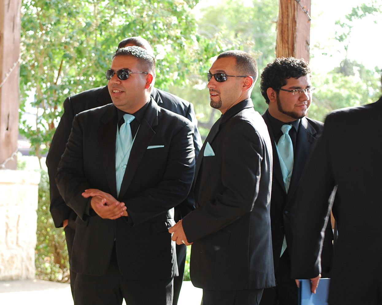 Groomsmen in dark suits and sunglasses line up outdoors. at venue, San Antonio wedding photography