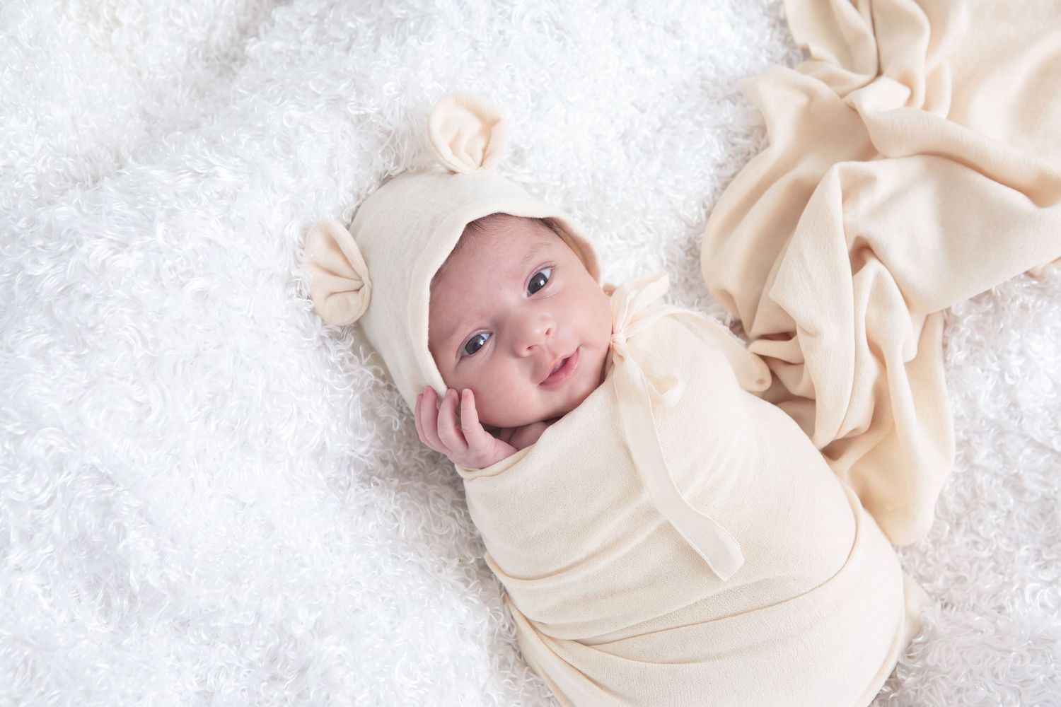 Newborn baby swaddled in a cream wrap during an In-Home newborn session in San Antonio, Texas. Precious Keepsakes Photography