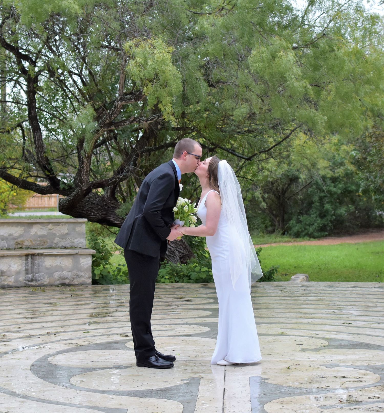 Wedding ceremony taking place on an outdoor stone patio surrounded by greenery. San Antonio wedding photographer