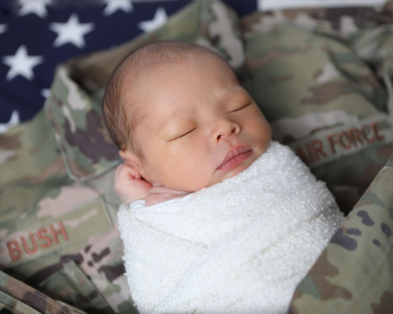 Newborn baby swaddled in white blanket sleeping on U.S. Air Force camouflage uniform photographer by Precious Keepsakes Photography San Anto
