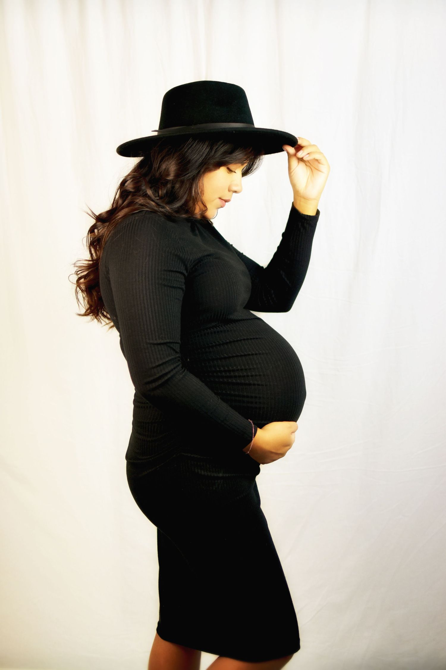 A mom to be holding her baby bump photographer by Precious Keepsakes Photography in San Antonio, Texas.