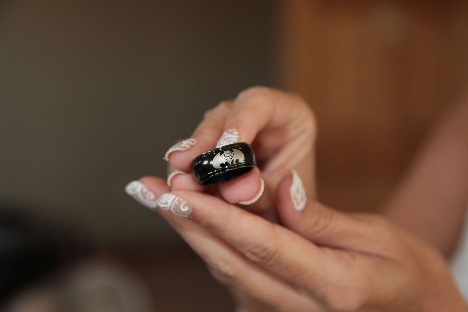 Close-up of hands with elegant white French tip nails holding a small black decorative item with silver details.