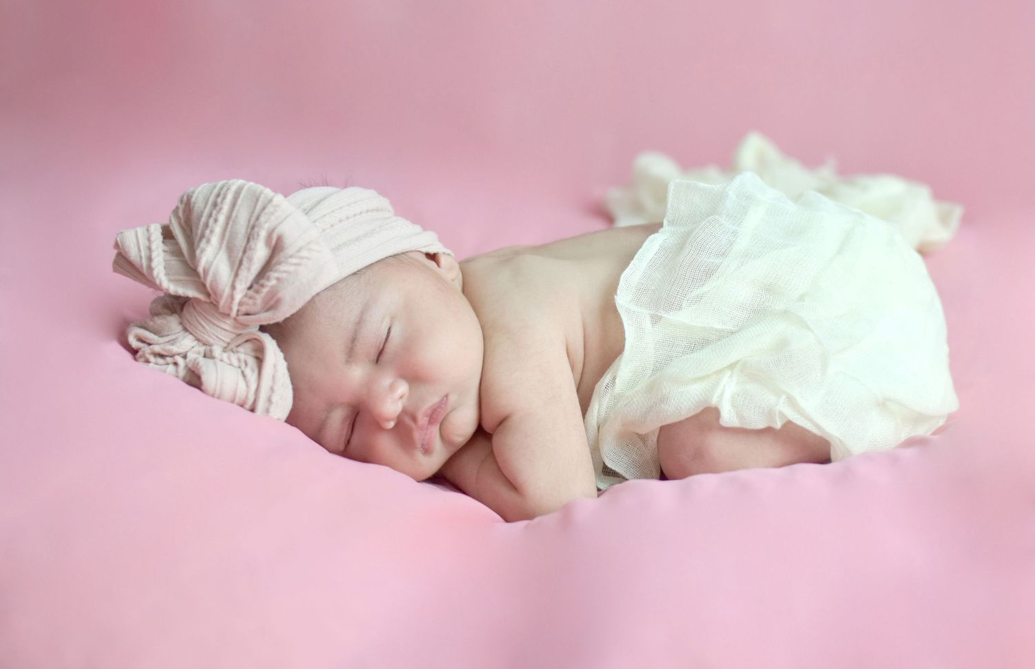 Sleeping newborn lying on pink blanket wearing a white tutu and headband, San Antonio newborn photography