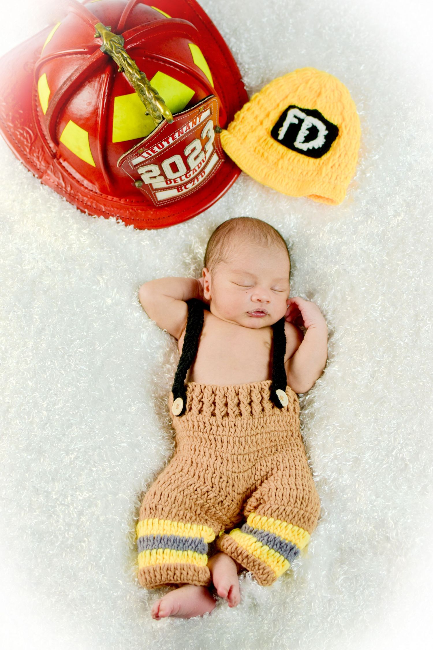 Creative newborn photo with firefighter outfit and dad's helmet, San Antonio newborn photography