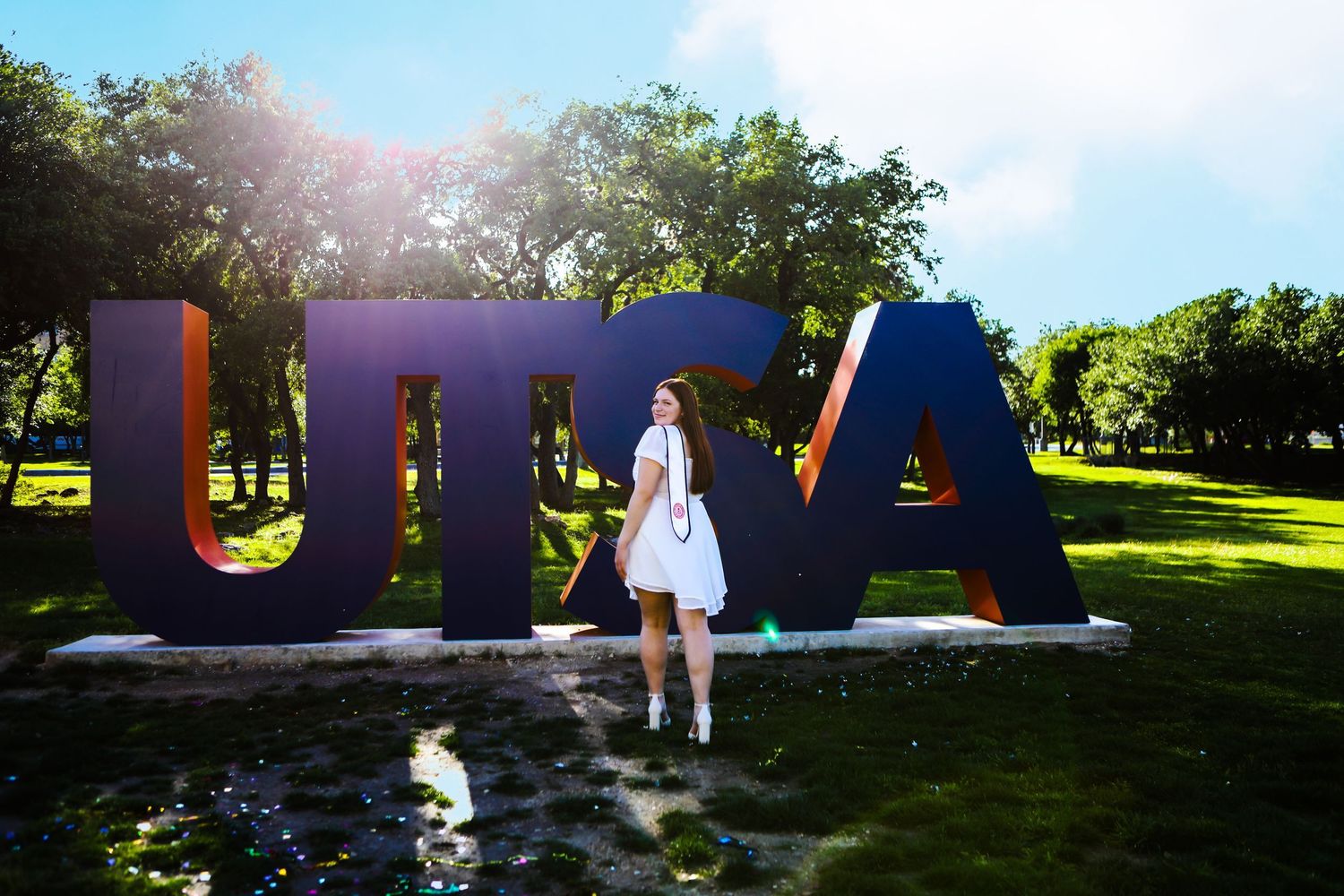 A UTSA graduate shows her excitement standing in front of the school sign in San Antonio, Texas. Senior portrait session