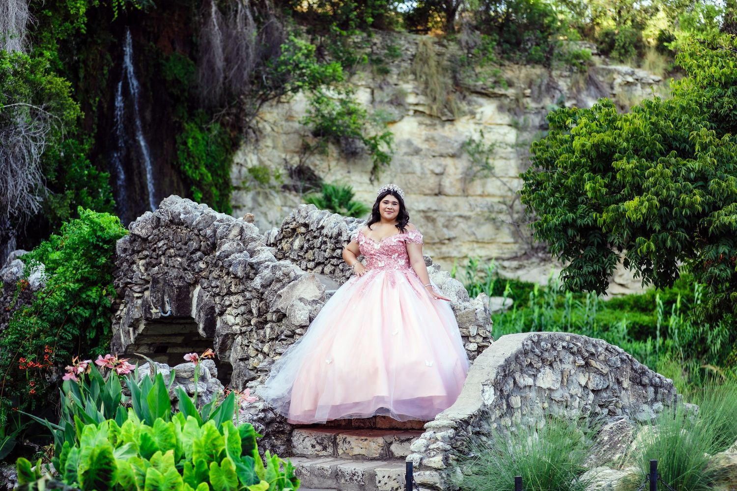 A Sweet 16 in a pink ball gown poses on bridge at Japanese Tea Gardens in San Antonio during her dress photography session.