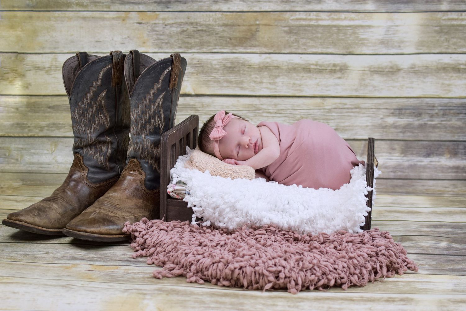 Western Rodeo themed newborn photo with cowboy boots and rustic wooden backdrop. San Antonio newborn photography