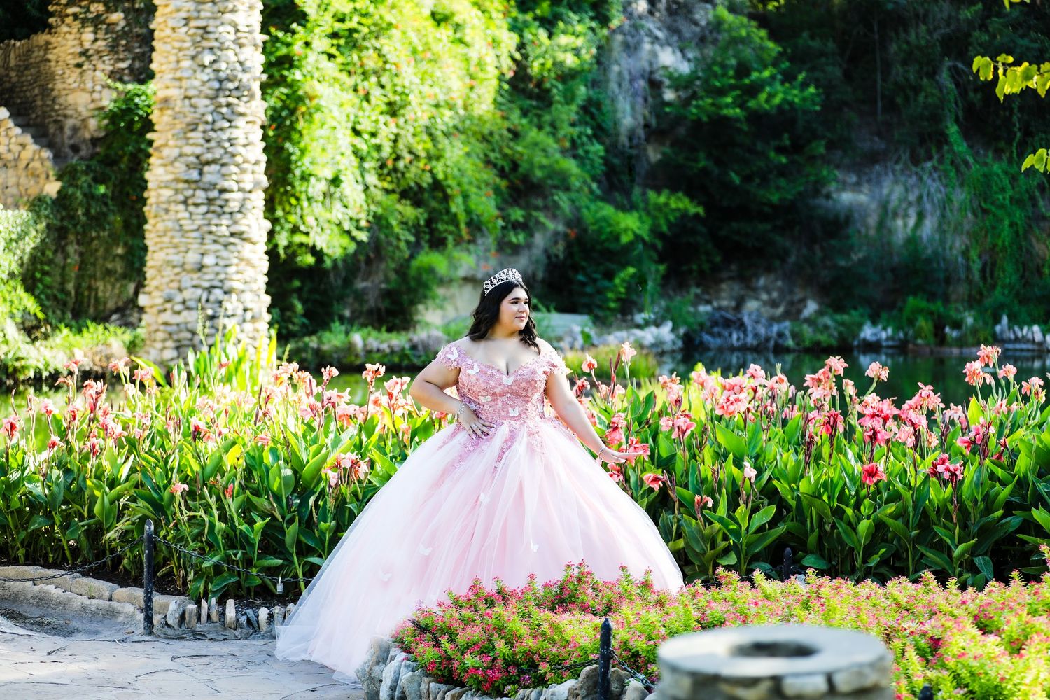 A sweet 16 in a pink gown poses elegantly among blooming tulips at Japanese Tea Garden in San Antonio at her photography session