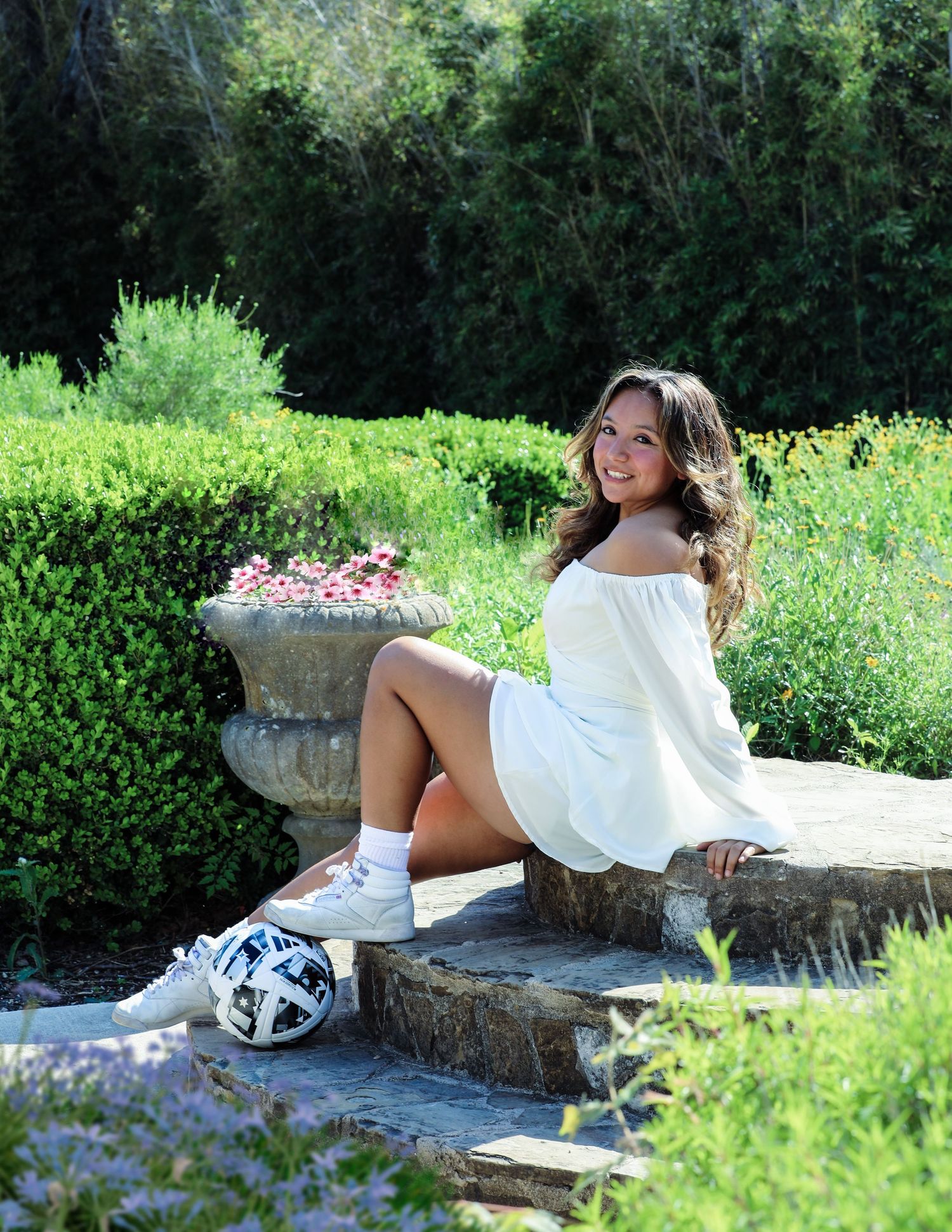 Excited student sits on steps at Landa Library at her senior photography session in San Antonio, Texas