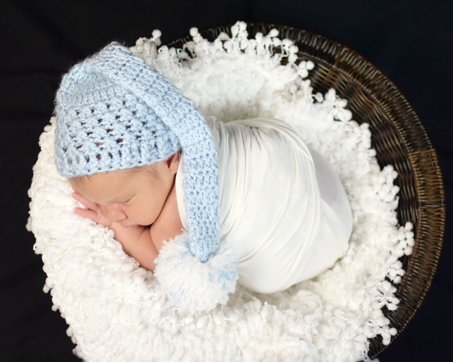 Baby boy wearing light blue knitted cap sleeping on fluffy white blanket. San Antonio newborn photography