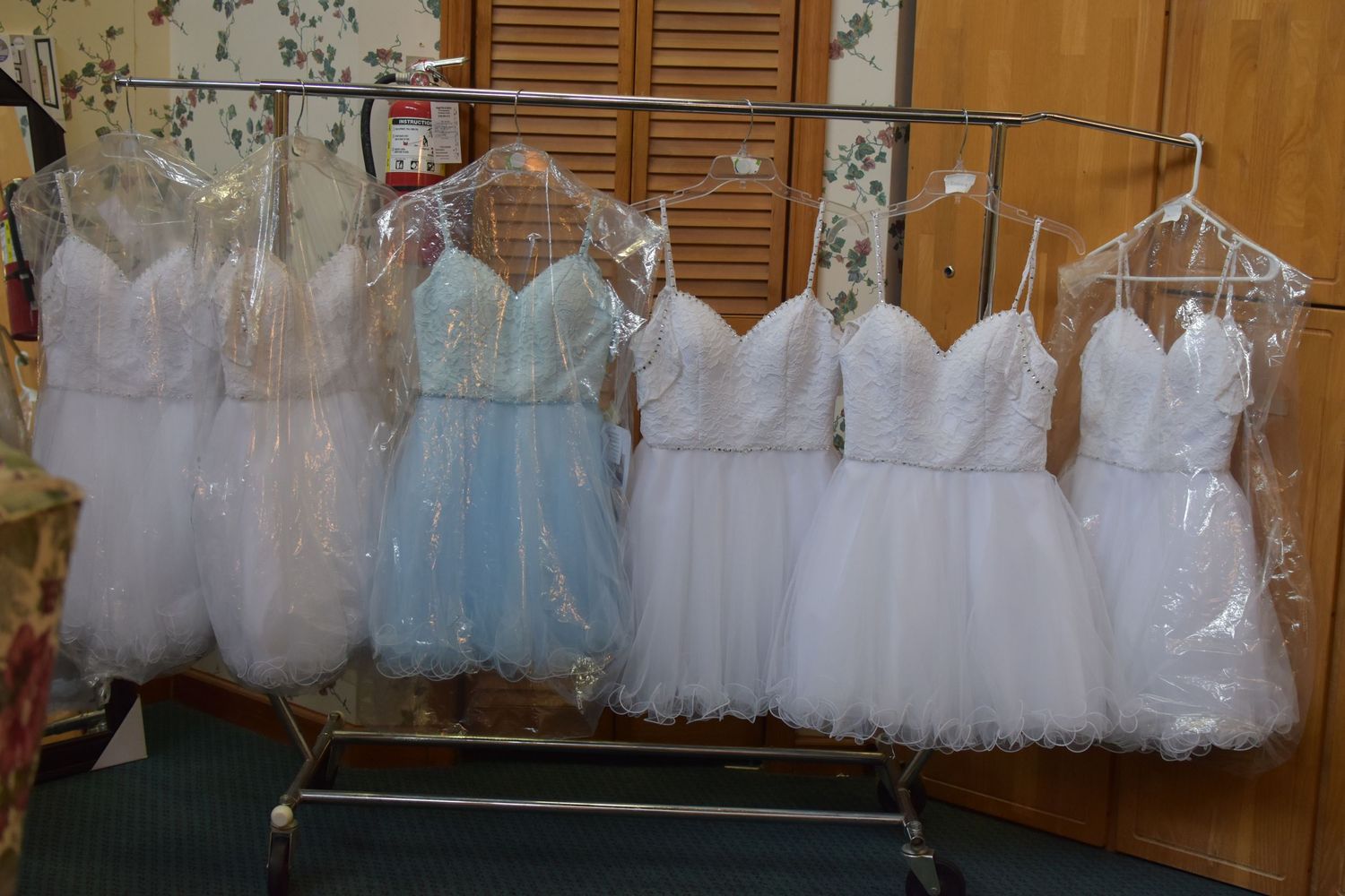 Row of white and light blue dresses hanging on display in a sweet 16 room before event starts in Northeast San Antonio, Texas.