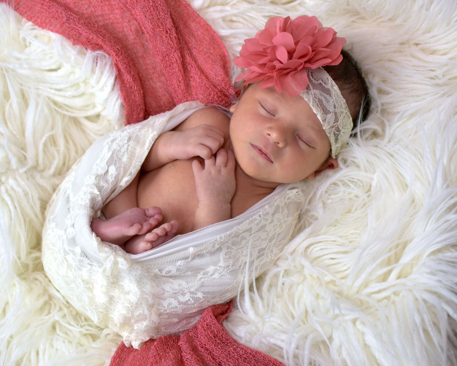 Baby girl in coral wrap sleeping peacefully on white fluffy blanket, San Antonio newborn photography