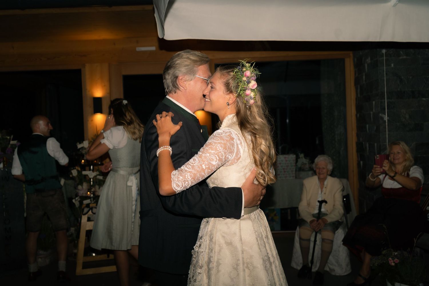 Bride shares a tender first dance kiss with her father at an elegant evening wedding reception.