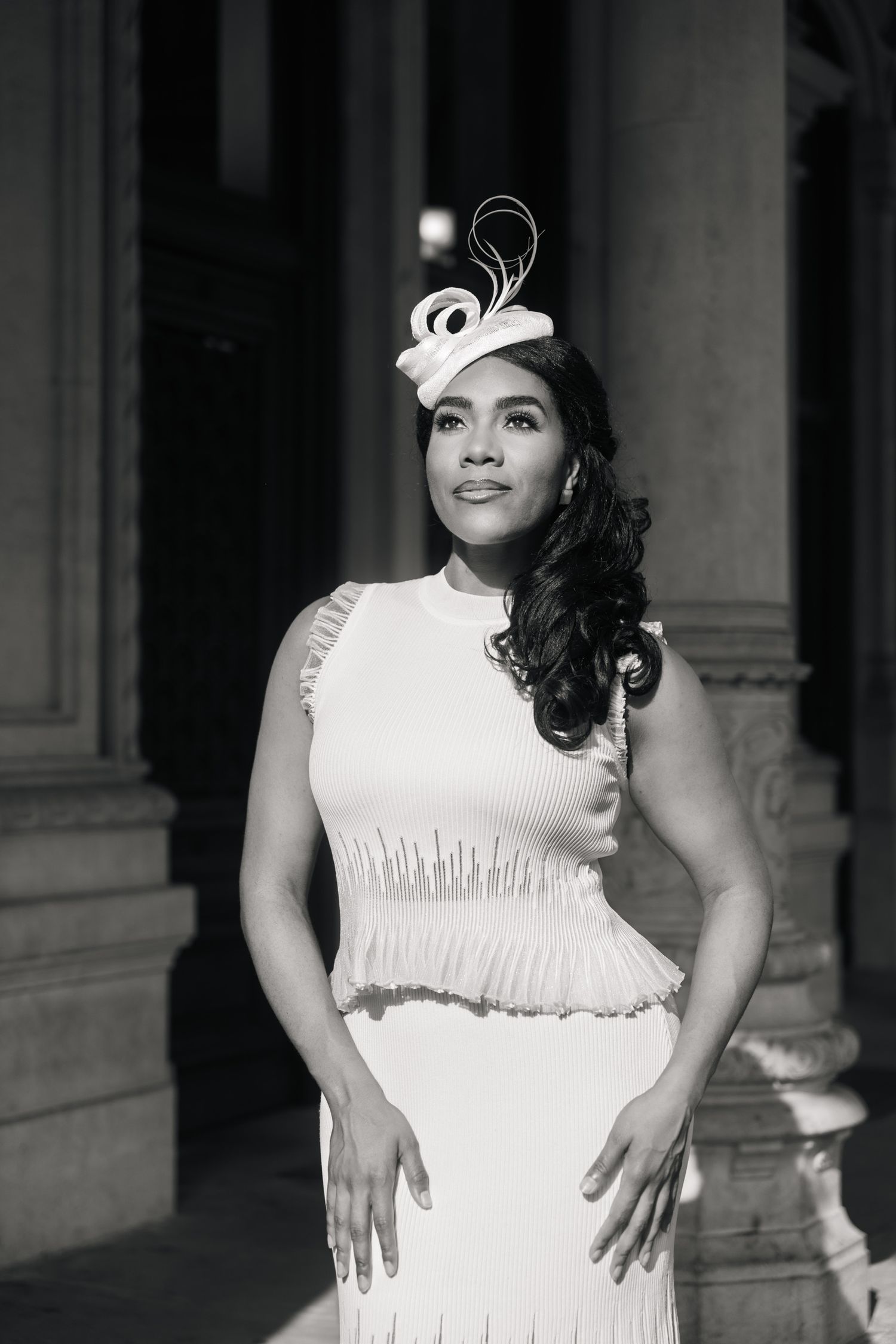 Black and white portrait of woman in white fringe dress and fascinator hat.