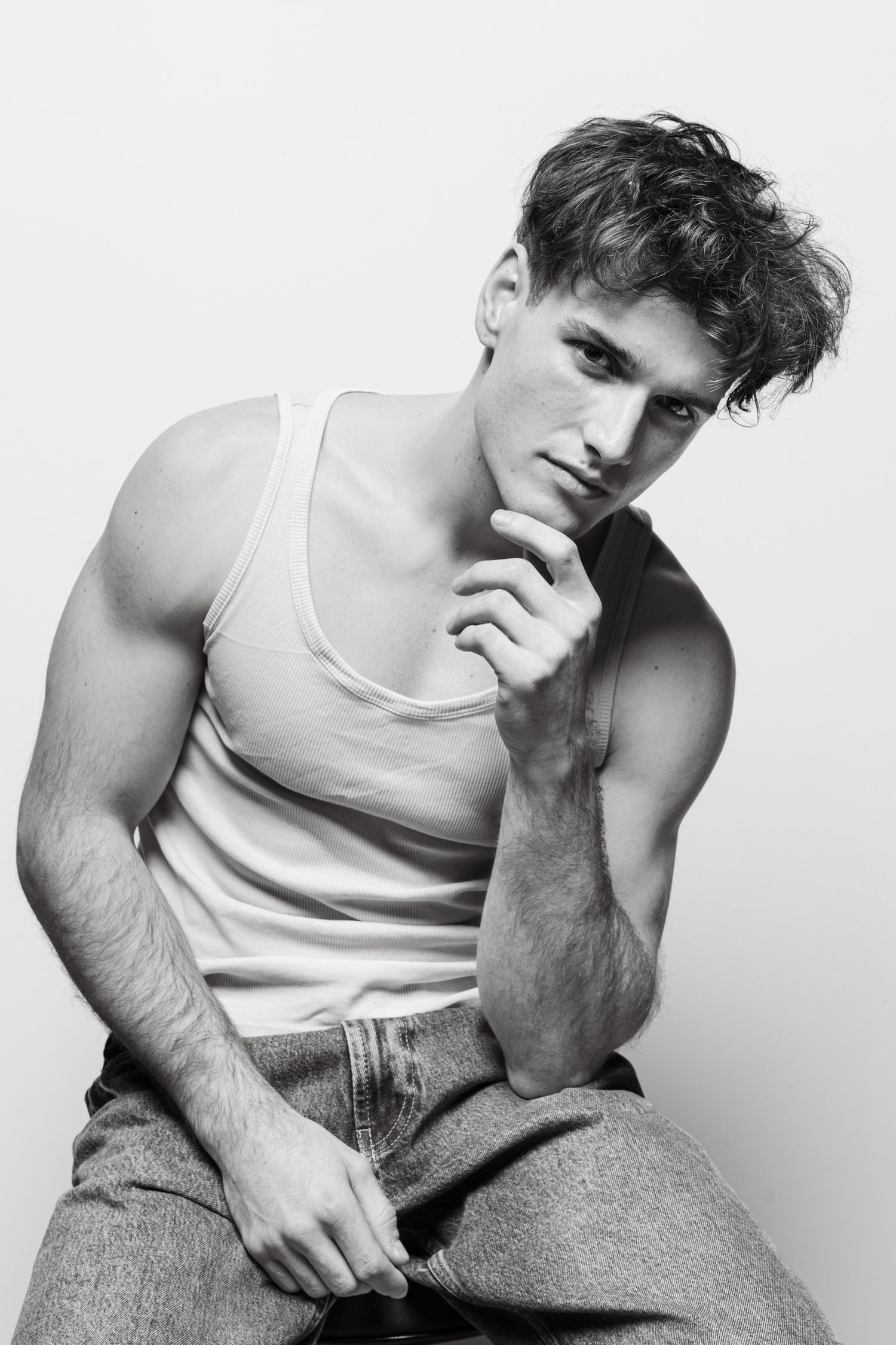 Black and white portrait of athletic man in white tank top and jeans.