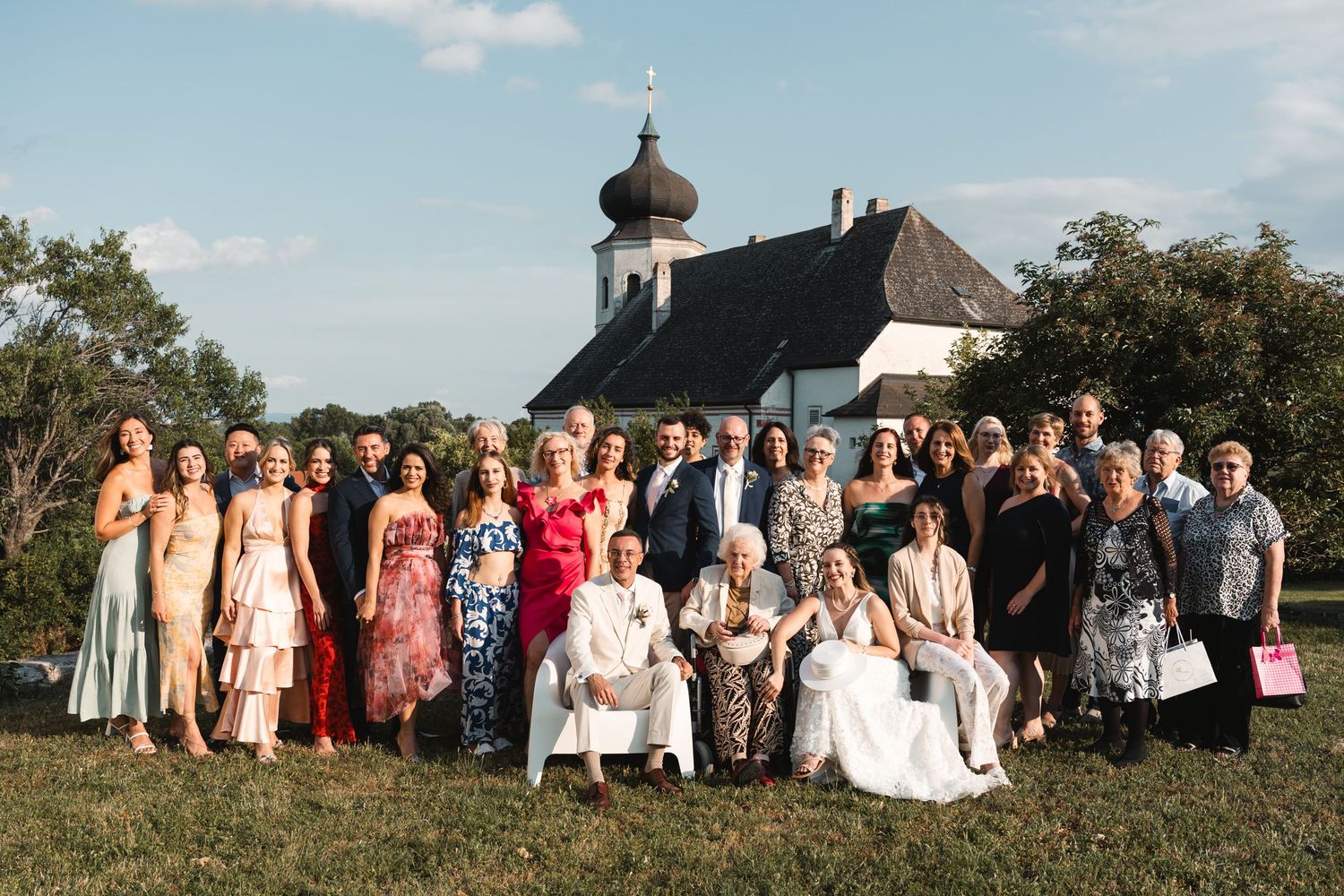Large wedding family group photo in front of a historic church at sunset.