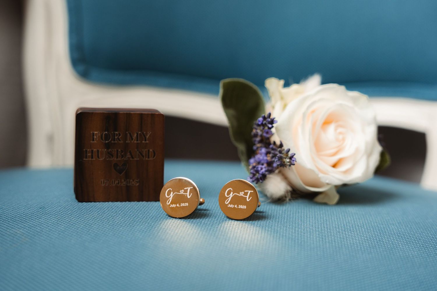 Personalized wooden cufflinks with engraved initials displayed beside a white rose boutonniere.