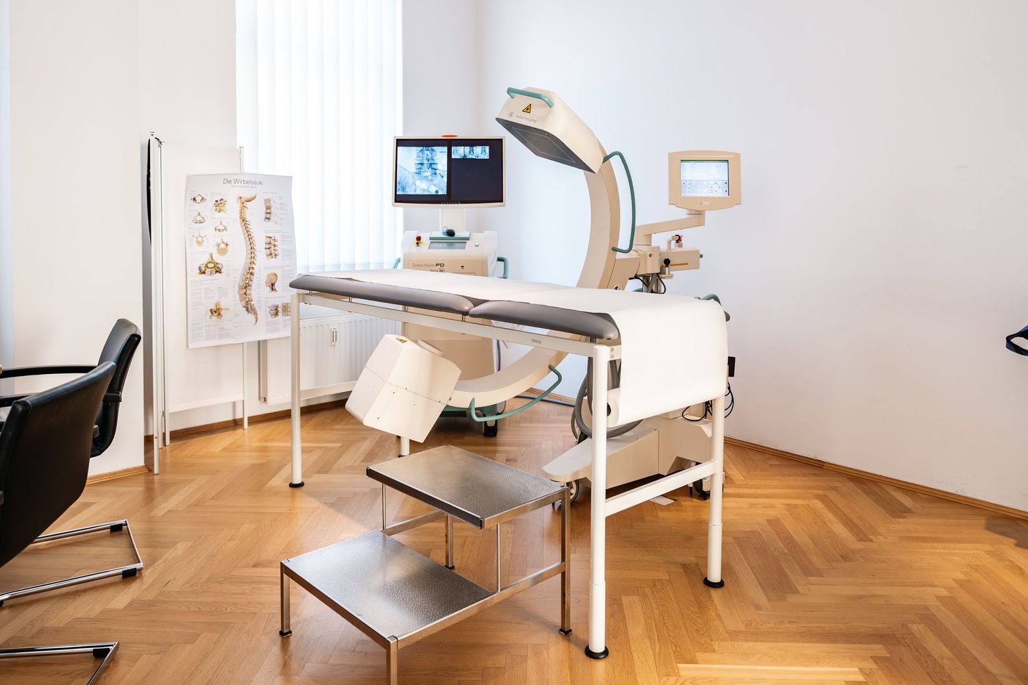 Modern medical examination room with specialized diagnostic equipment on herringbone parquet floor.