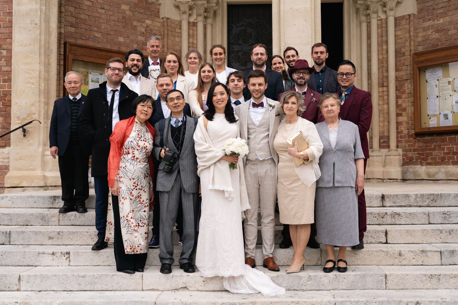 Wedding group photo of diverse guests posing on church steps with bride and groom.