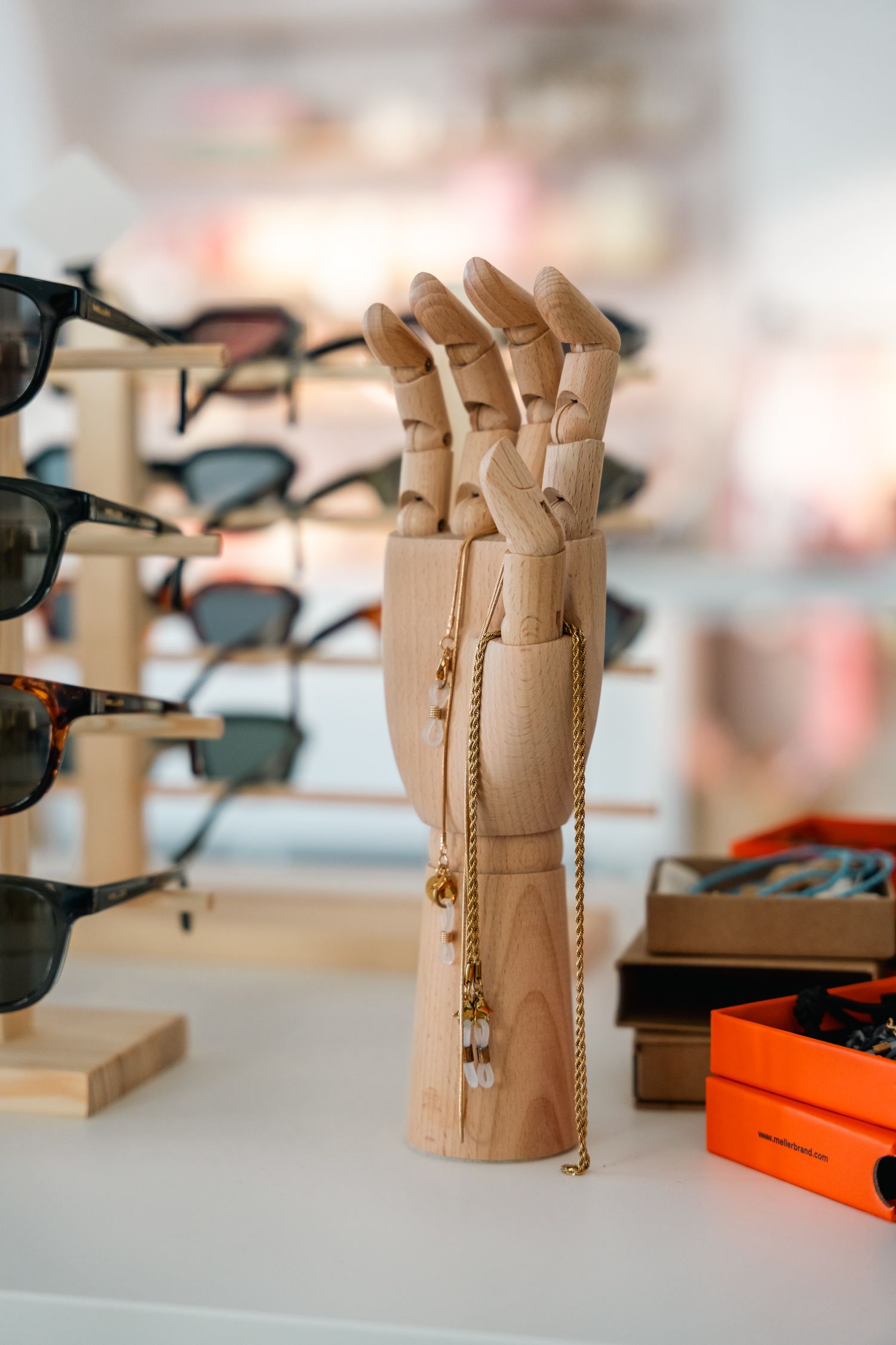 Wooden articulated hand display holding necklace in sunglasses store.