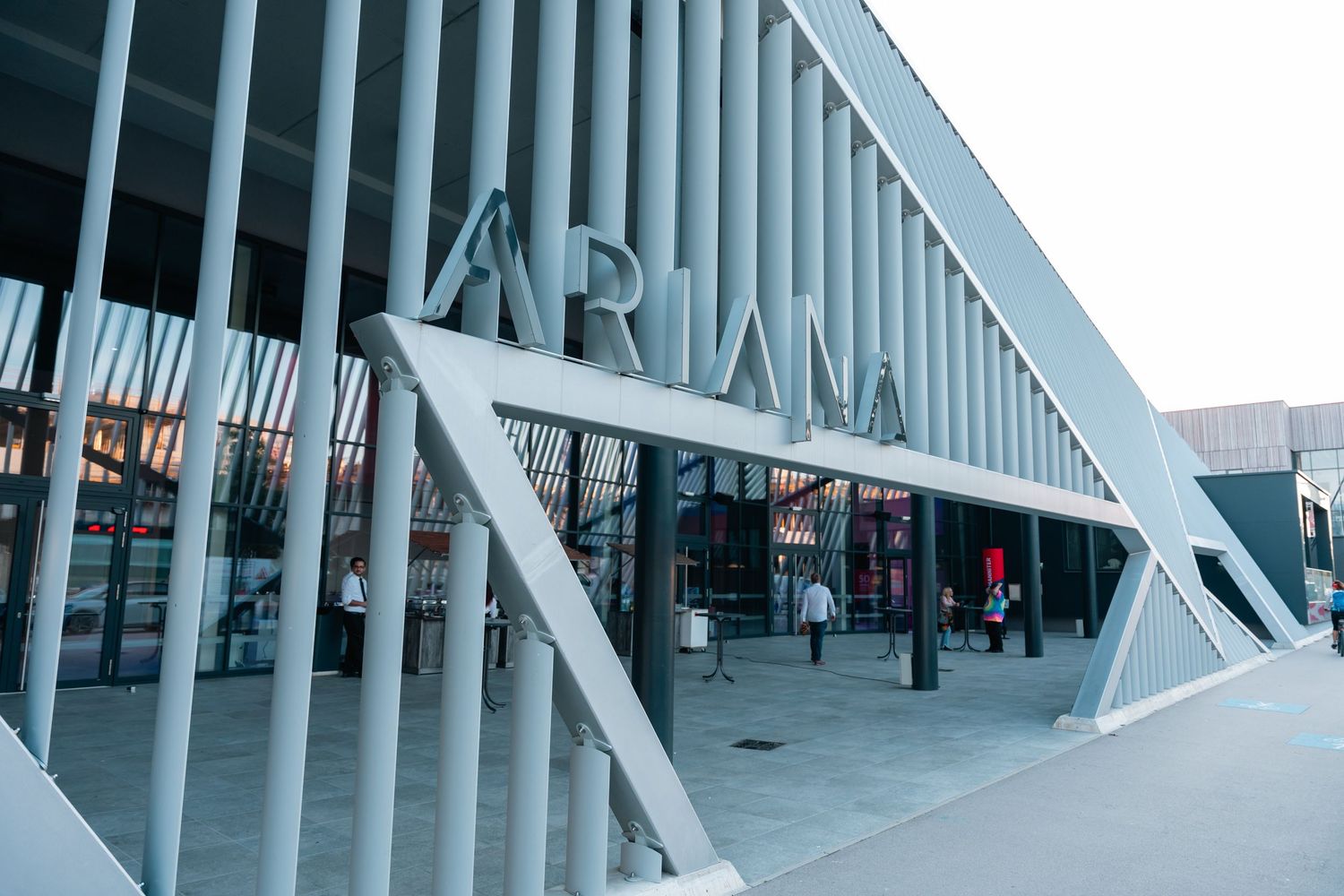 Modern arena building exterior featuring bold ARENA signage with geometric steel architectural design at dusk.