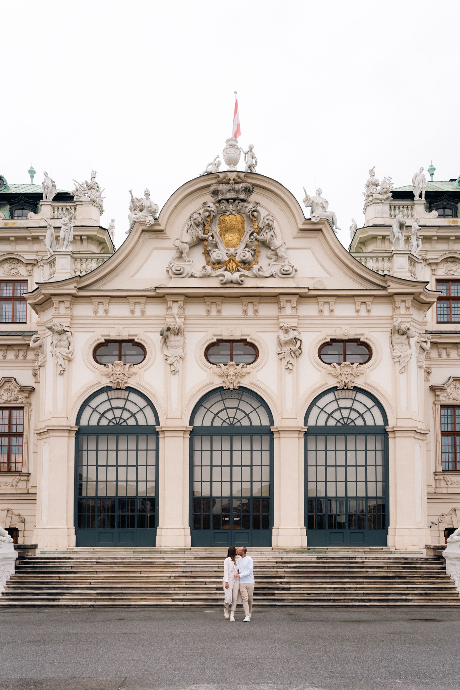 Couple embracing before ornate Baroque facade of Upper Belvedere Palace in Vienna Austria.