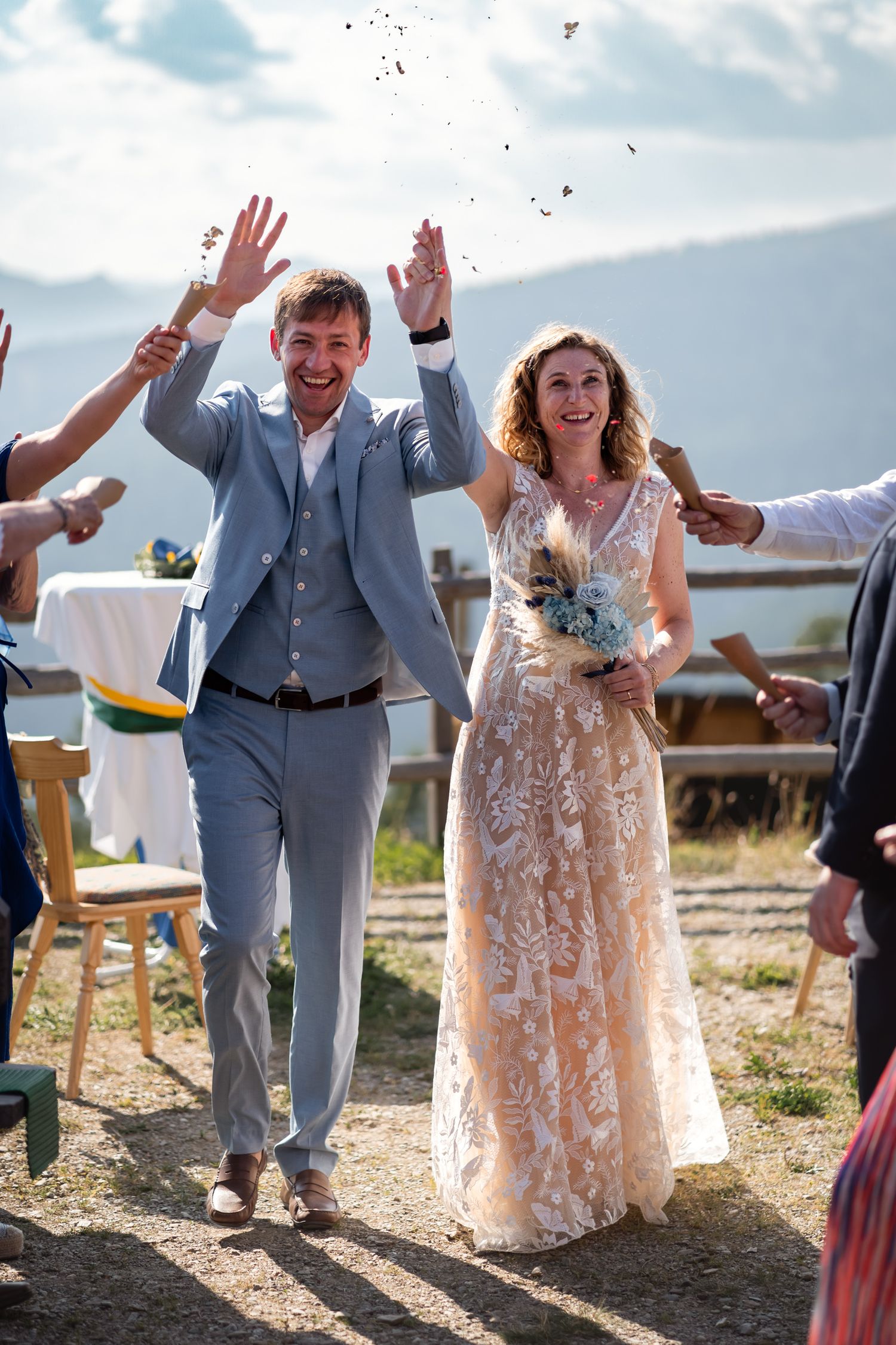 Joyful newlyweds walk down the aisle as guests toss confetti at outdoor ceremony.