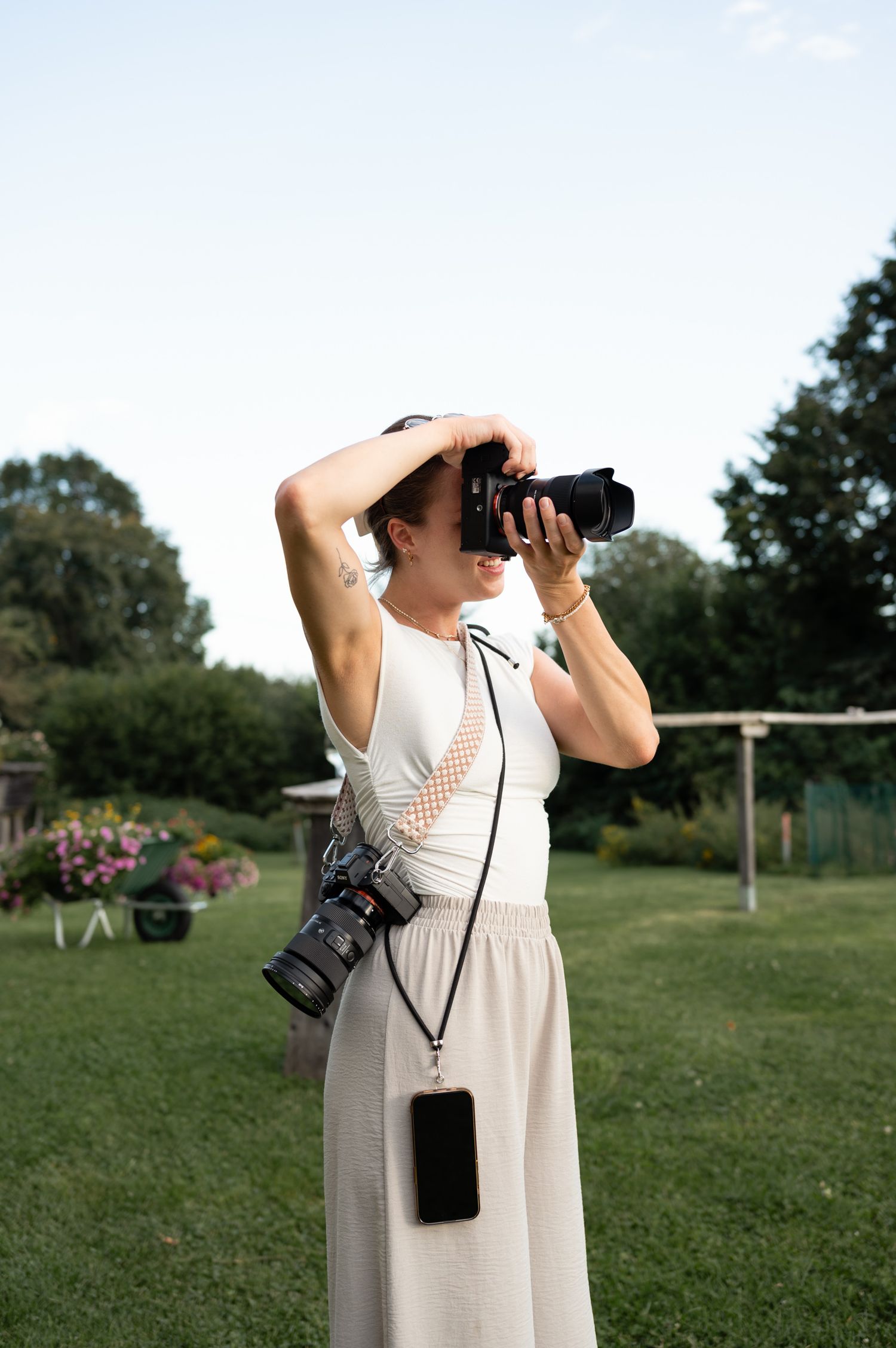 Woman photographer capturing shots with DSLR camera in green garden setting.