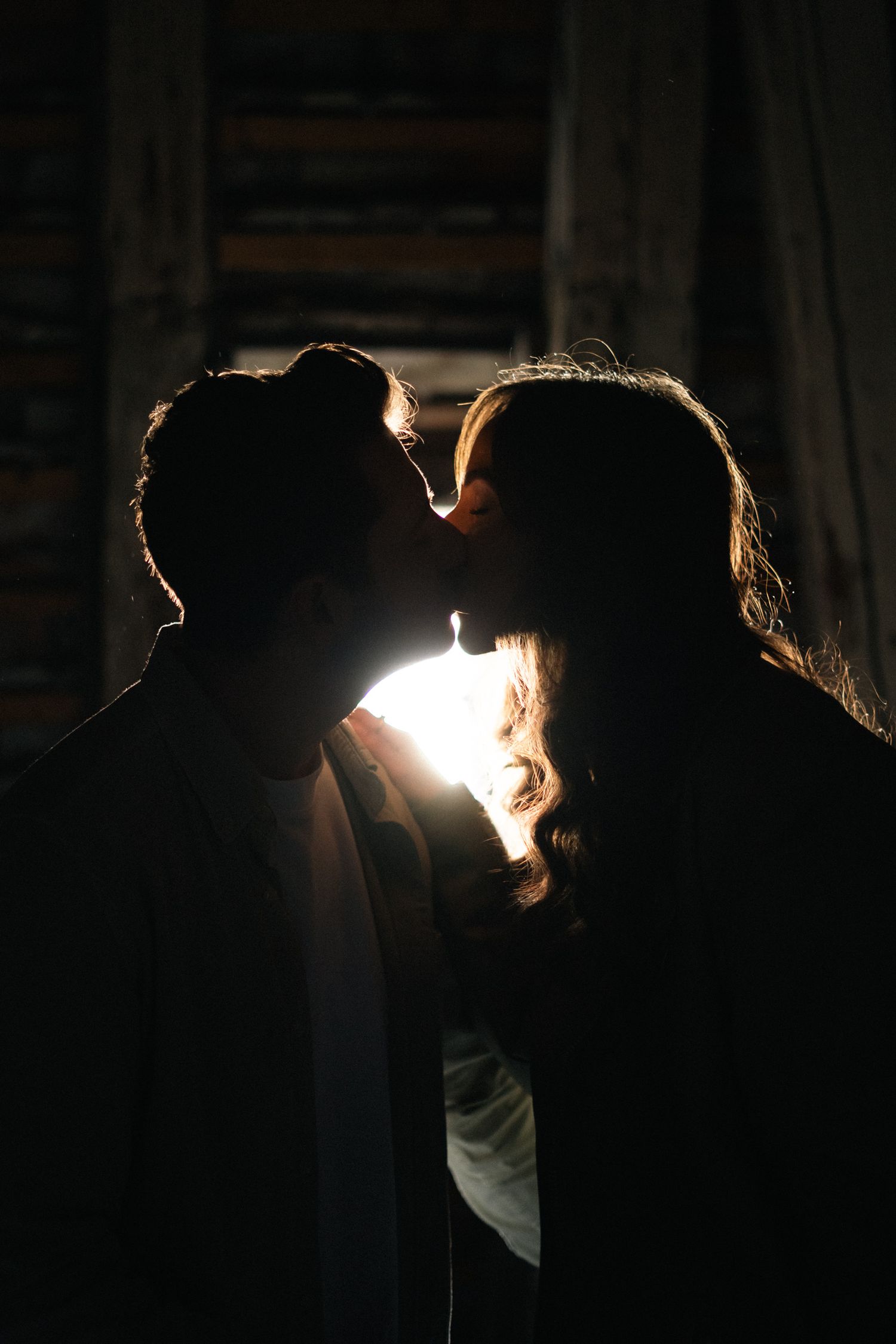 Romantic couple silhouette kissing with backlight in dark setting.