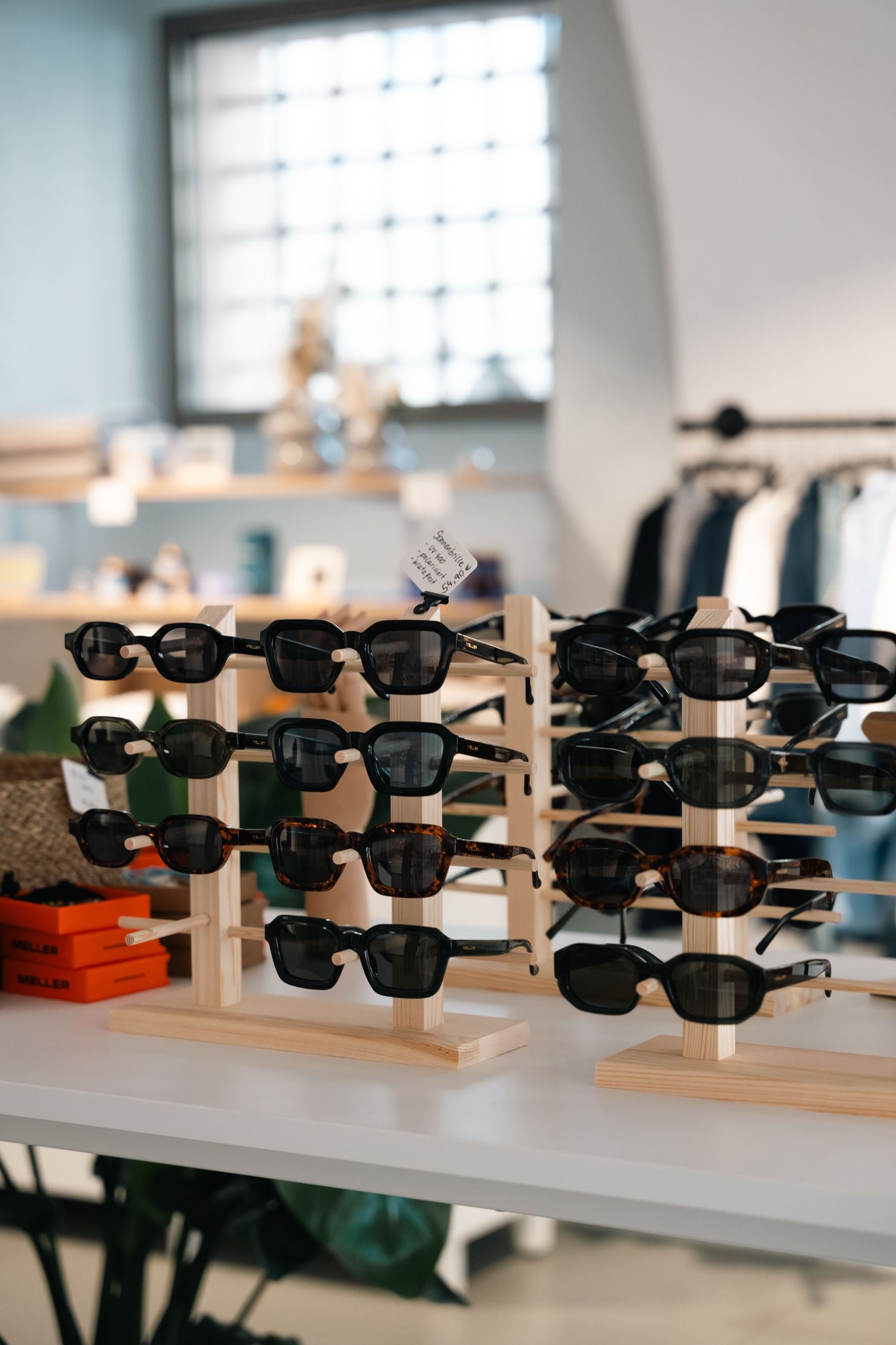 Multiple black sunglasses displayed on wooden tiered stands in a bright modern retail store.