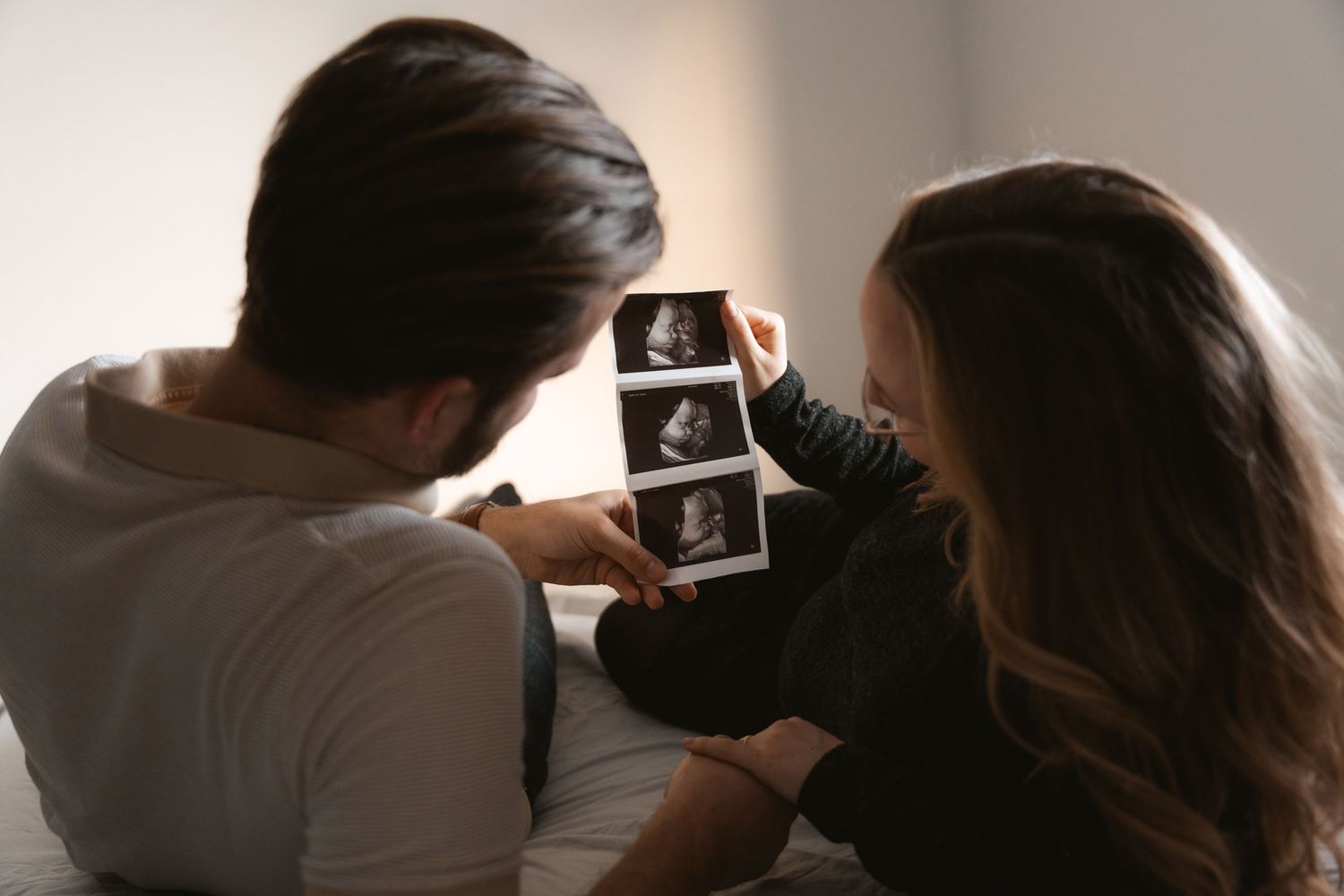 Couple sitting together reviewing ultrasound photos of their baby during pregnancy.