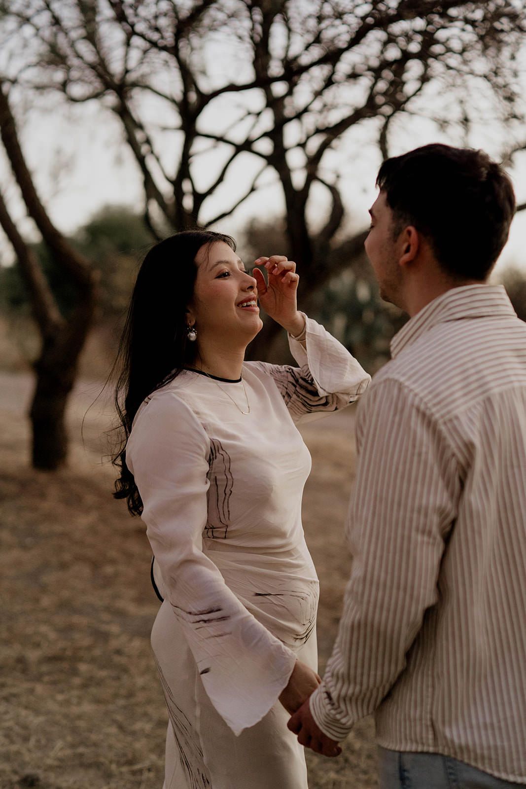 A couple shares joyful dance moves together in a natural outdoor setting.