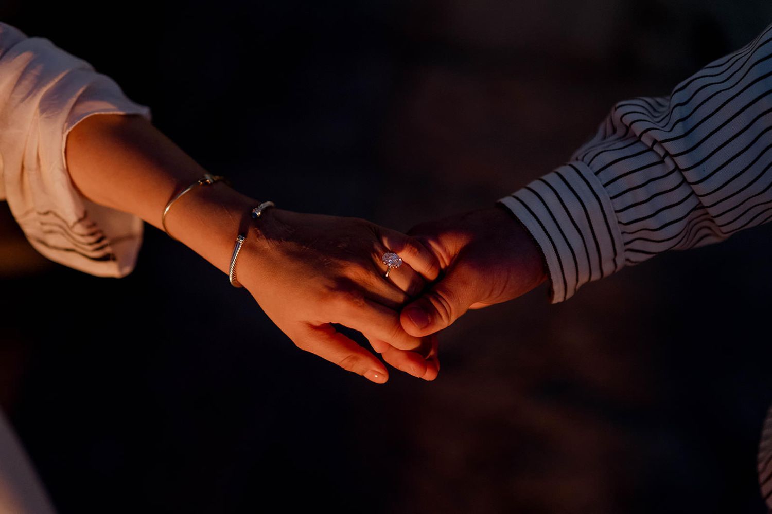 Close-up of hands during an intimate moment at sunset.