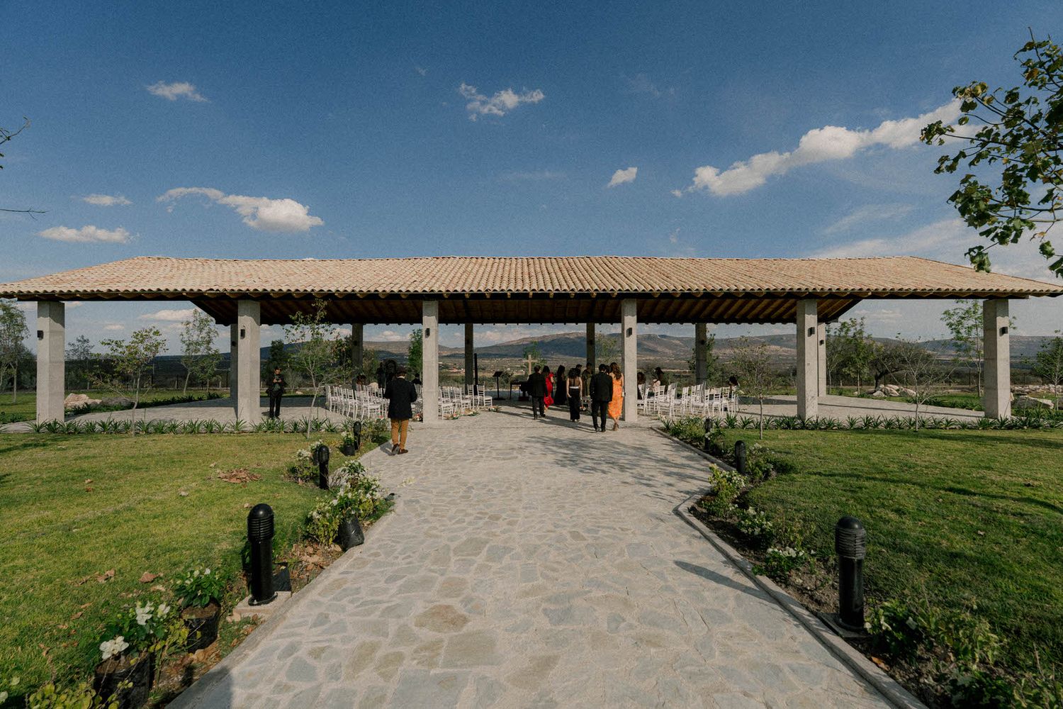 A stone pathway leads to an elegant covered pavilion surrounded by manicured gardens.