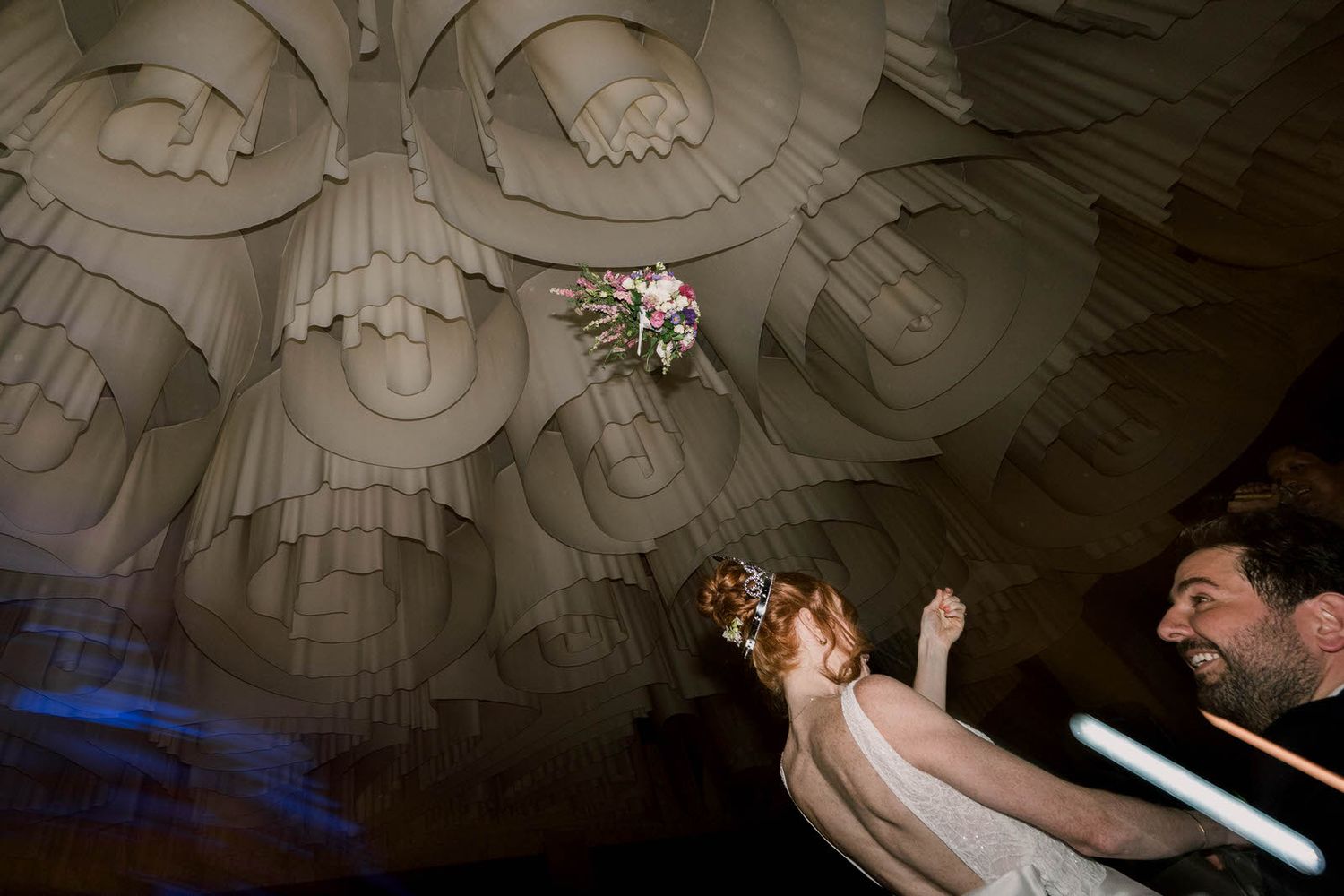 A wedding celebration under an ornate ceiling with decorative architectural details.