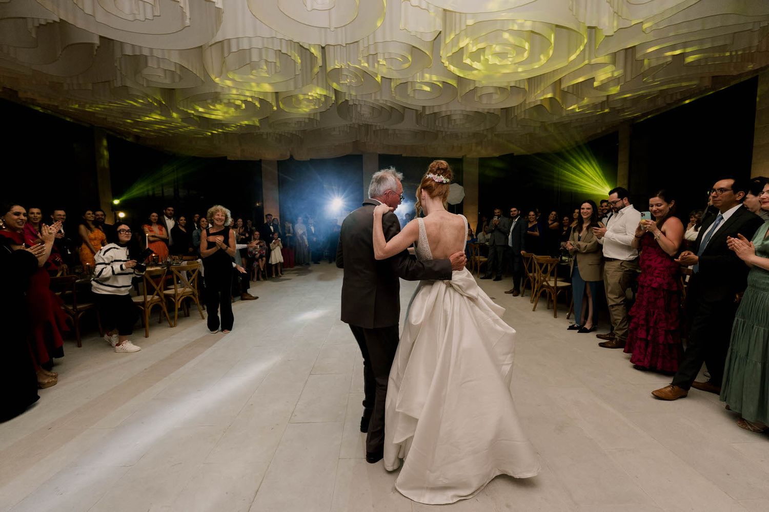 Wide view of a wedding reception dance floor with guests gathered around the perimeter.