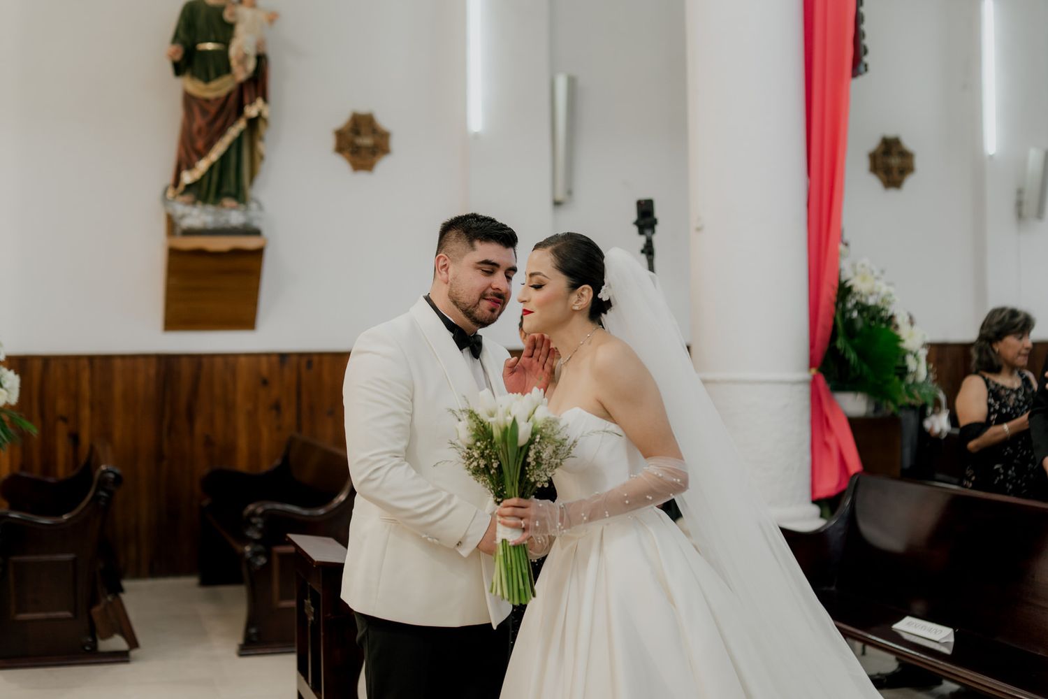 Joyful wedding ceremony moment captured in church with white and red decor.