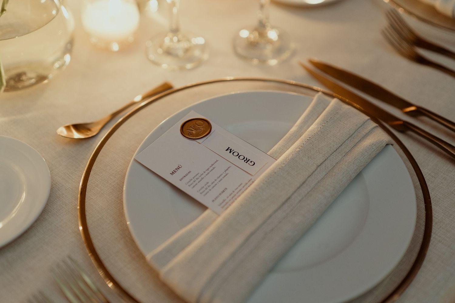 Close-up of elegant place settings with gold-rimmed plates and menu cards.