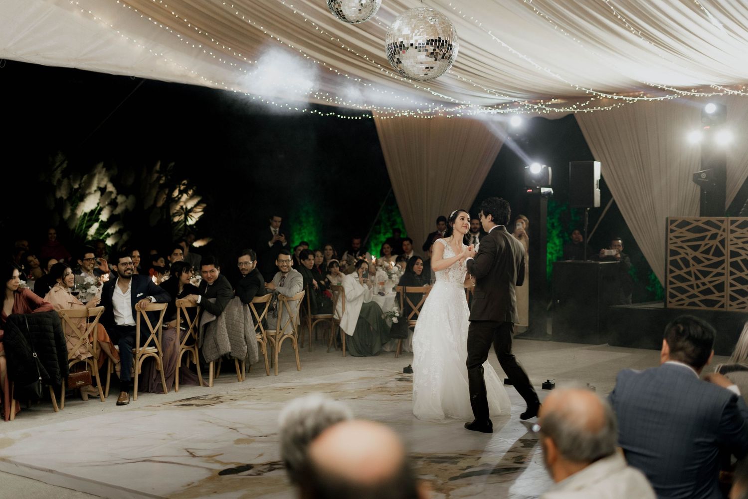 Wedding celebration venue with elegant draping and ambient lighting during evening festivities.
