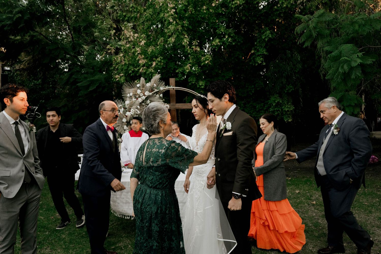 Wedding guests mingling at an outdoor garden reception with formal attire.