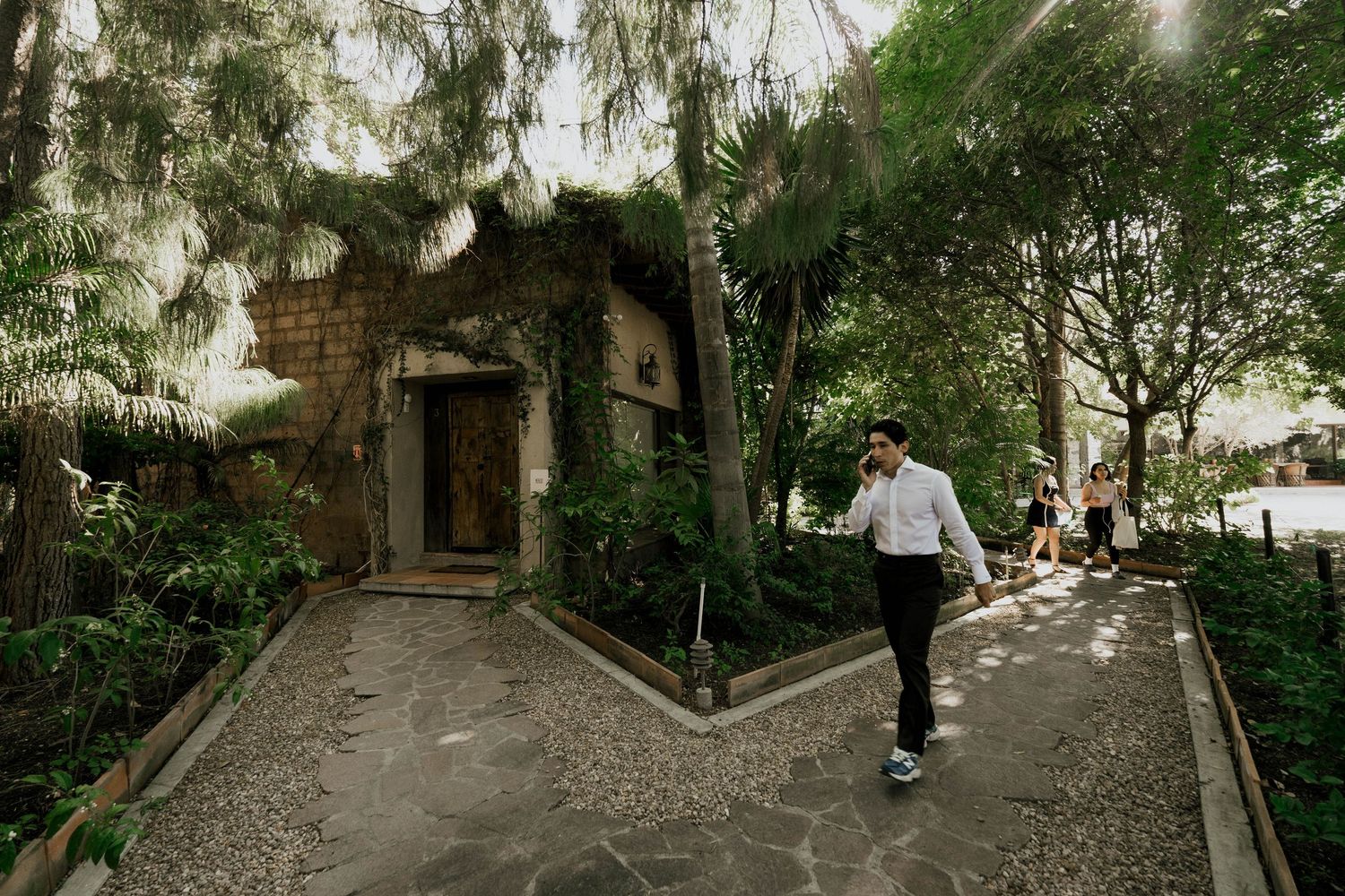 Stone pathway leading to rustic entrance with person walking in garden setting.