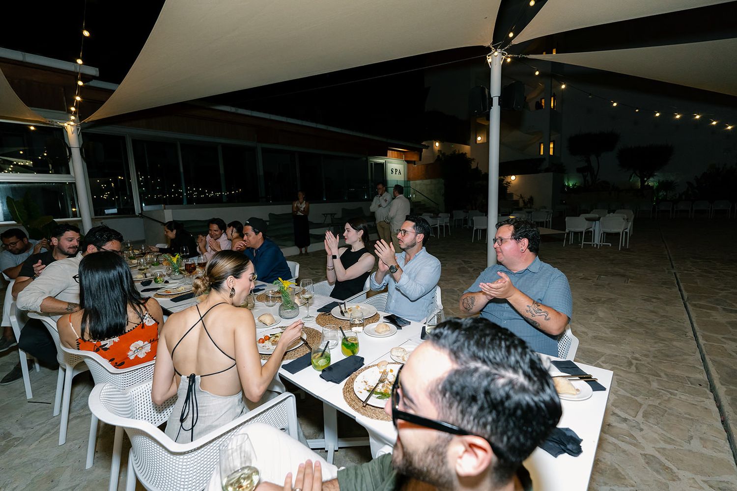 People gathered at outdoor tables for a casual evening social event or dinner party.