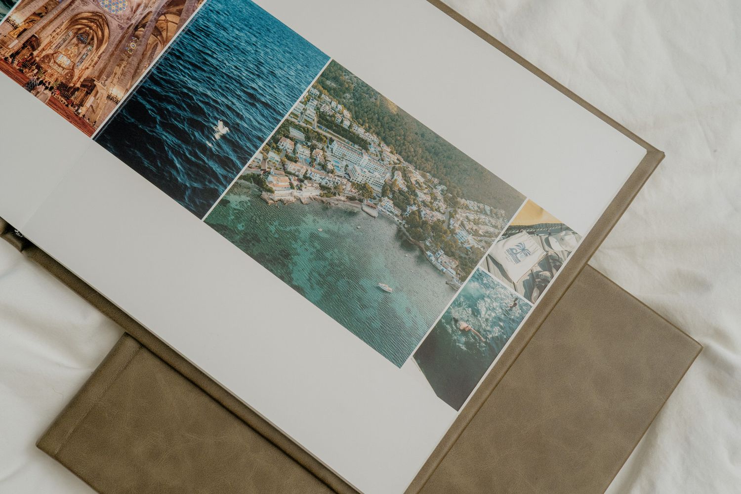A photo book open to a page displaying aerial and coastal travel photos, resting on a neutral linen surface.