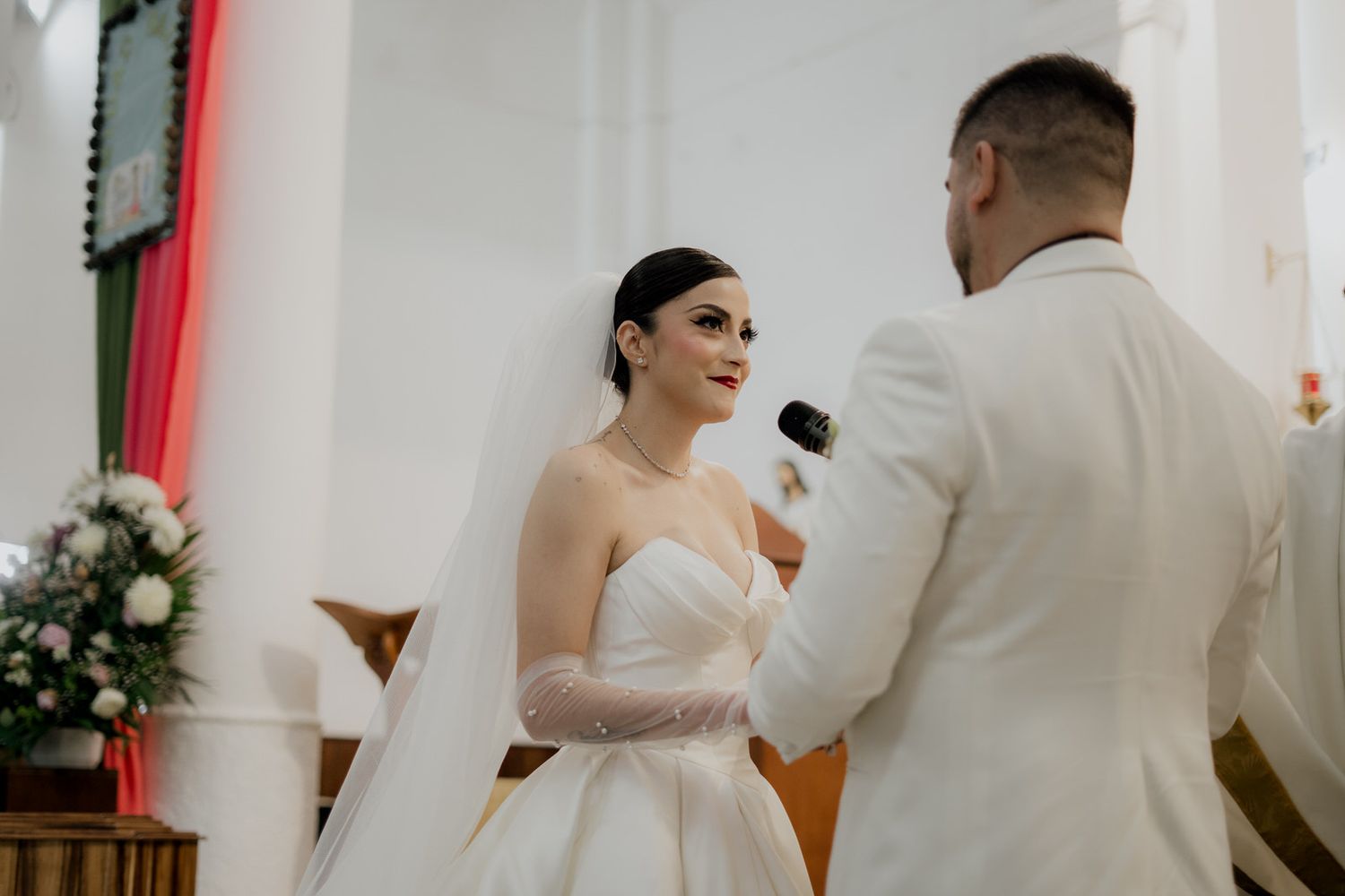 Intimate moment during a wedding ceremony with white and red church decor.