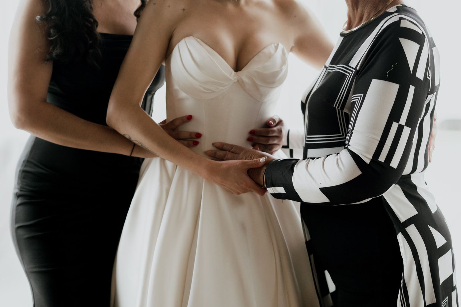 Wedding dress adjustments being made in a light-filled room.