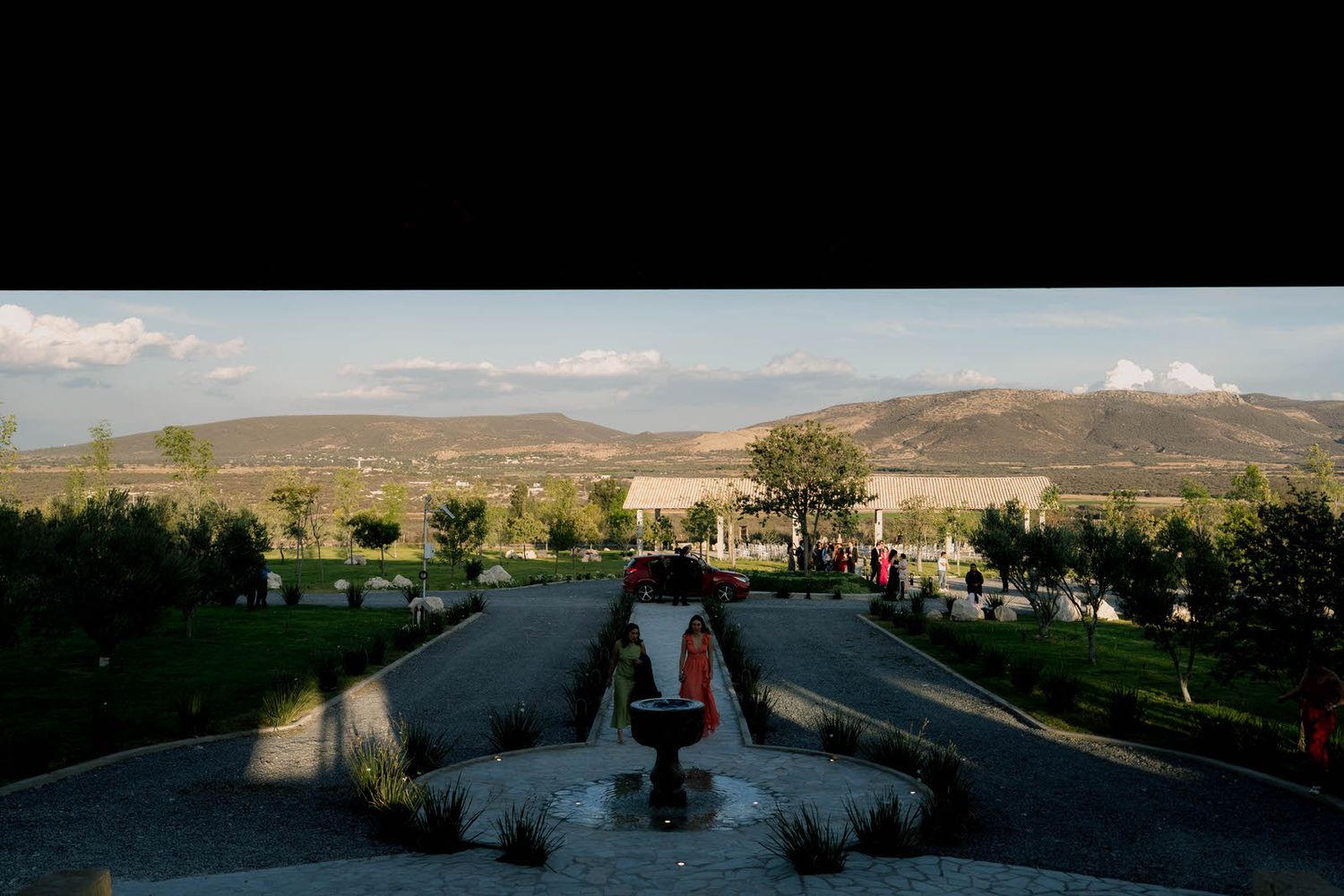 Panoramic view of an outdoor wedding venue with mountain landscape and fountain.