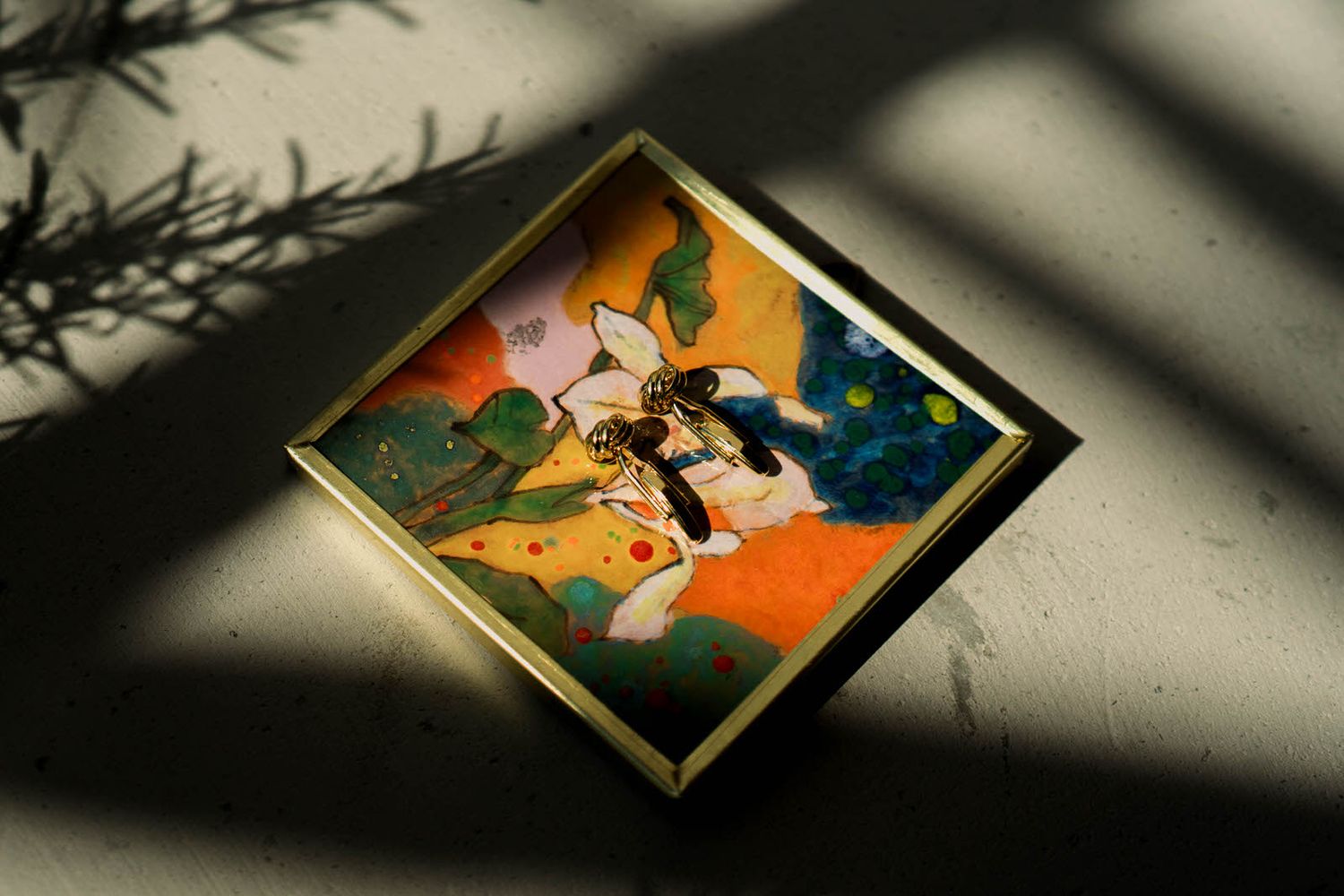 Artistic shadows cast on wall with framed artwork creating dramatic lighting effects.