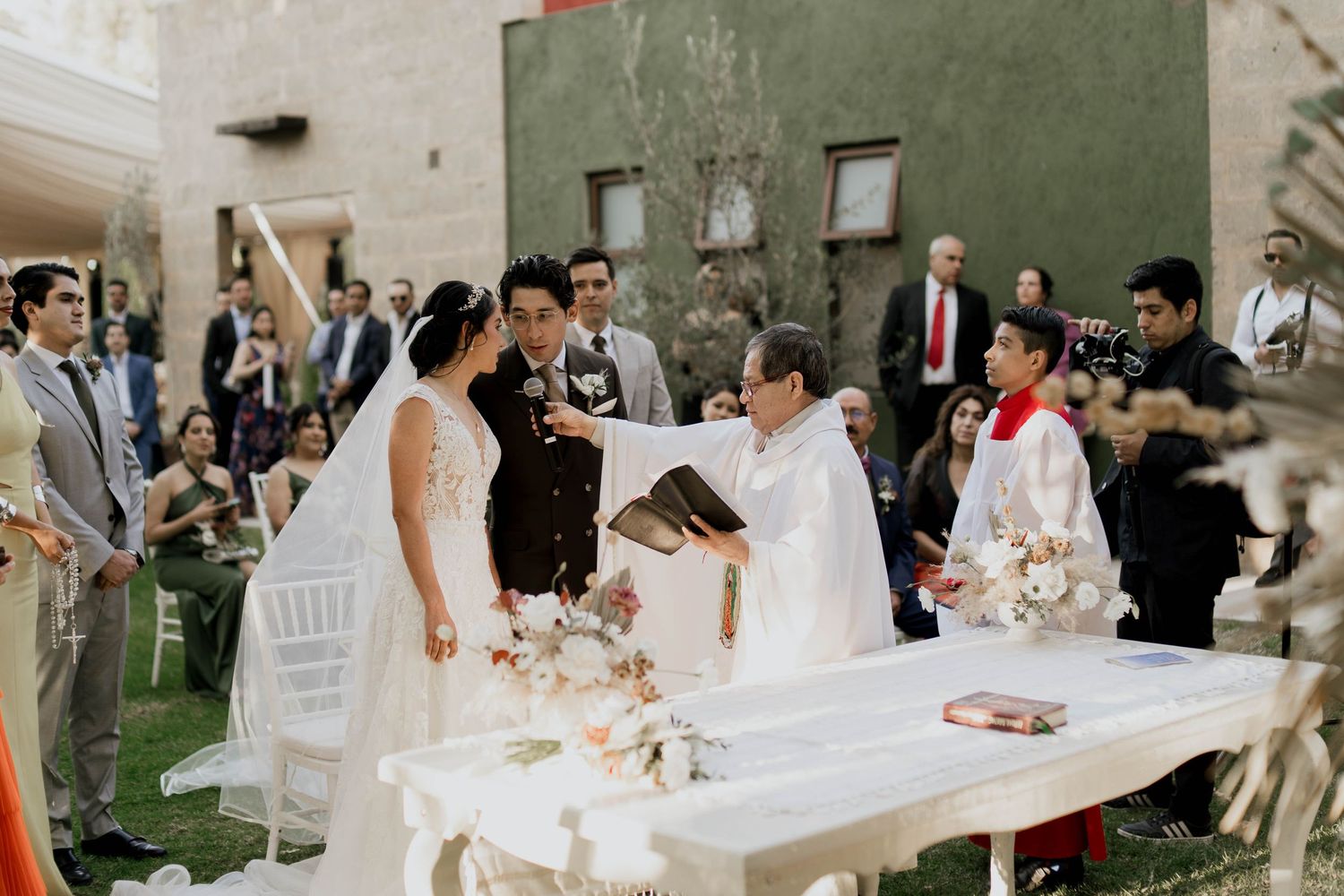 Wedding celebration scene with guests seated at tables decorated in white linens.