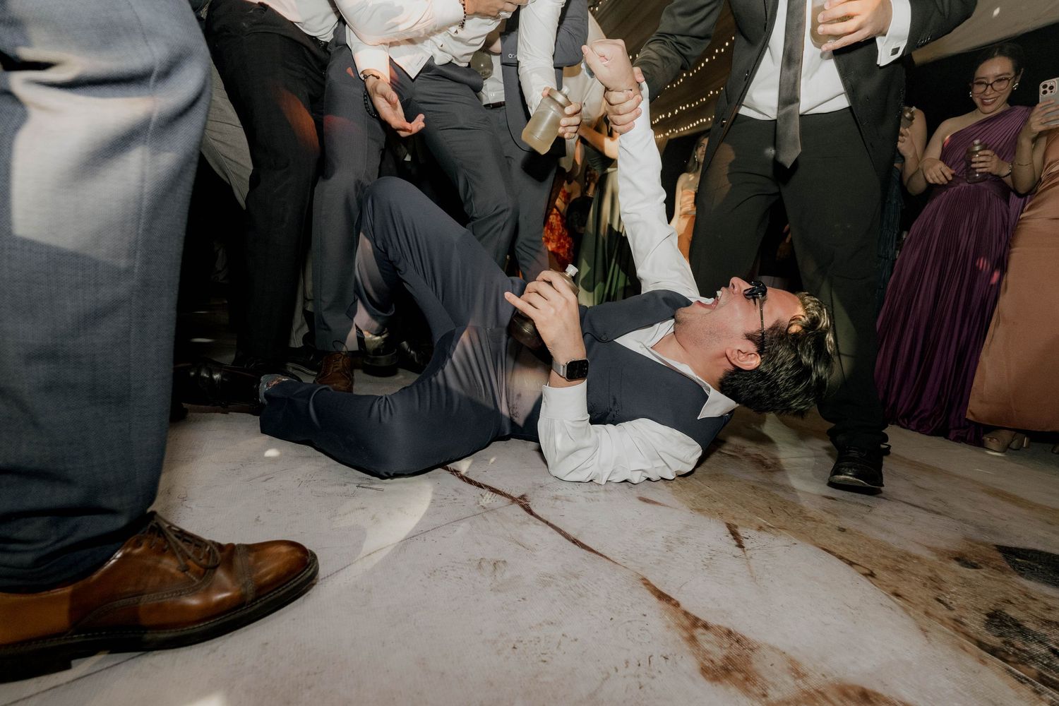 Wedding party guests dancing energetically on a dance floor at a reception celebration.